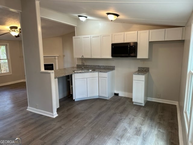 kitchen with lofted ceiling, white cabinetry, sink, and dark wood-type flooring