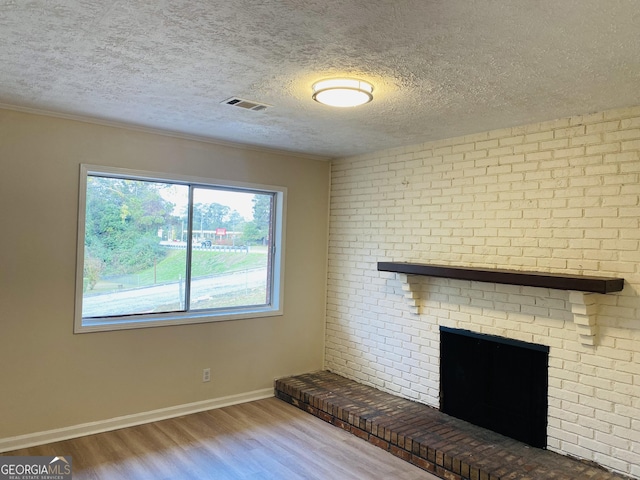 unfurnished living room with hardwood / wood-style floors, a fireplace, and a textured ceiling