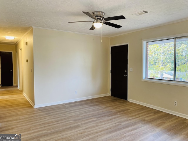 empty room with a textured ceiling, light wood-type flooring, ceiling fan, and crown molding