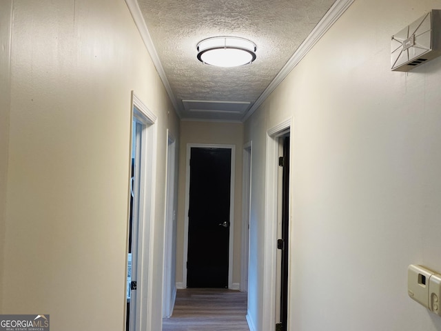 hallway with hardwood / wood-style flooring, ornamental molding, and a textured ceiling