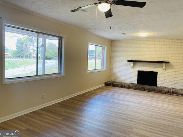 unfurnished living room with a wealth of natural light, hardwood / wood-style floors, and a brick fireplace