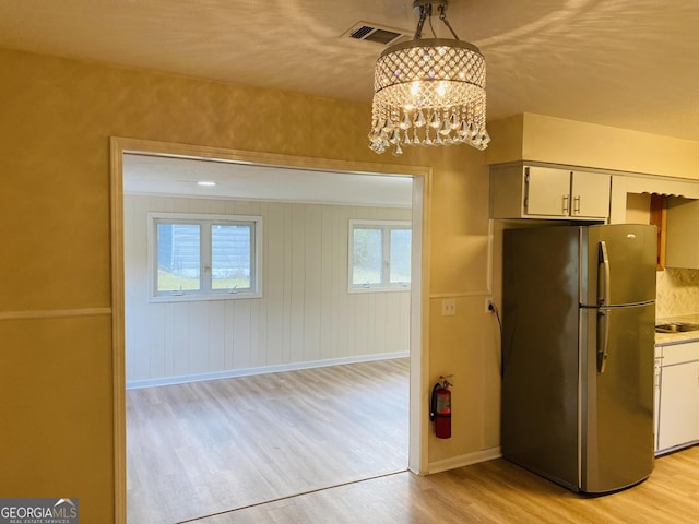 kitchen featuring stainless steel fridge, an inviting chandelier, light hardwood / wood-style flooring, and hanging light fixtures