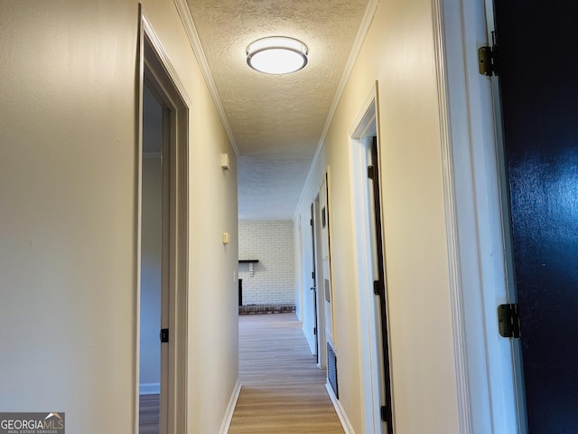 corridor featuring a textured ceiling, light hardwood / wood-style floors, and ornamental molding