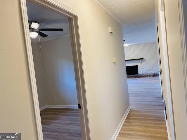 corridor with ornamental molding and light wood-type flooring