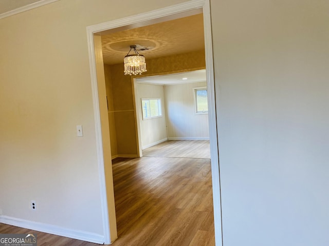 hall with a chandelier, hardwood / wood-style flooring, and crown molding