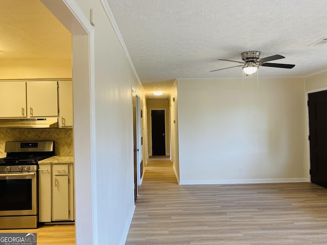 kitchen featuring decorative backsplash, stainless steel stove, light hardwood / wood-style floors, and a textured ceiling