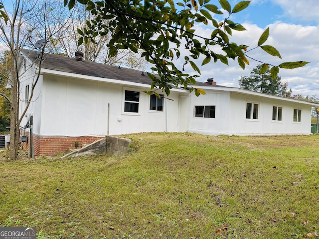 rear view of property with central AC unit and a lawn