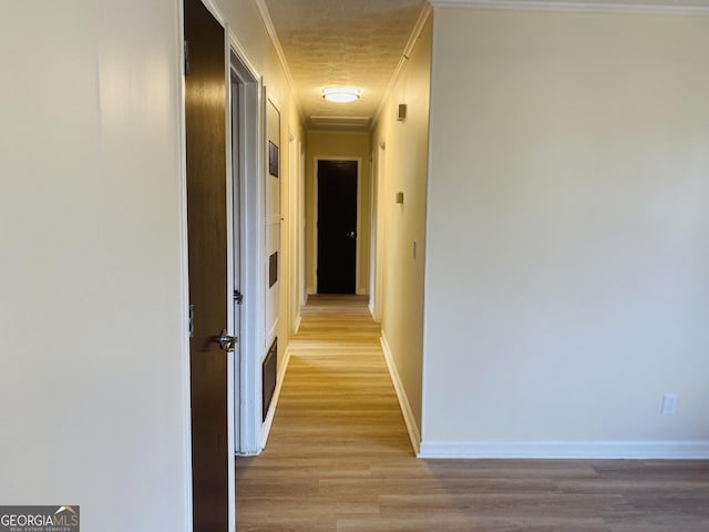 corridor featuring light wood-type flooring and crown molding