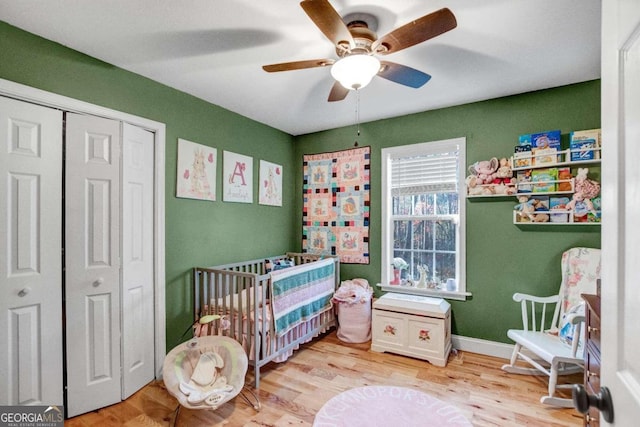 bedroom featuring ceiling fan, light hardwood / wood-style floors, a closet, and a nursery area