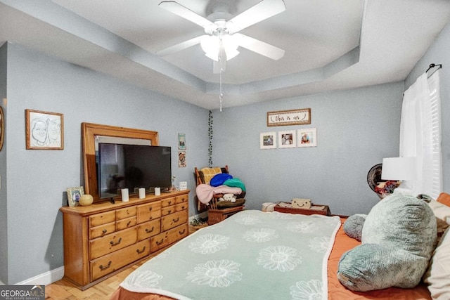 bedroom featuring a raised ceiling and ceiling fan