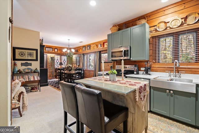 kitchen with sink, stainless steel appliances, decorative light fixtures, light carpet, and a breakfast bar