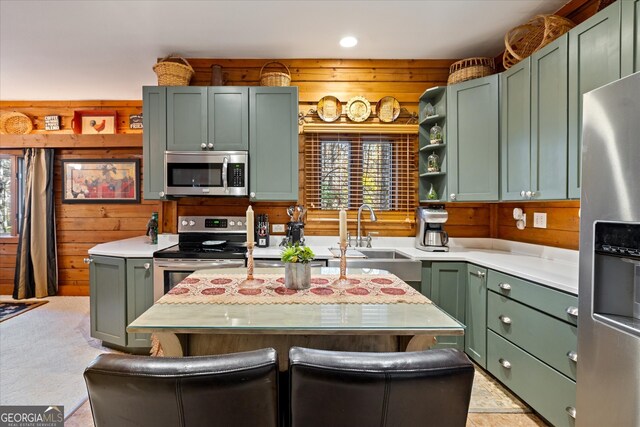 kitchen with sink, wooden walls, green cabinetry, appliances with stainless steel finishes, and light colored carpet