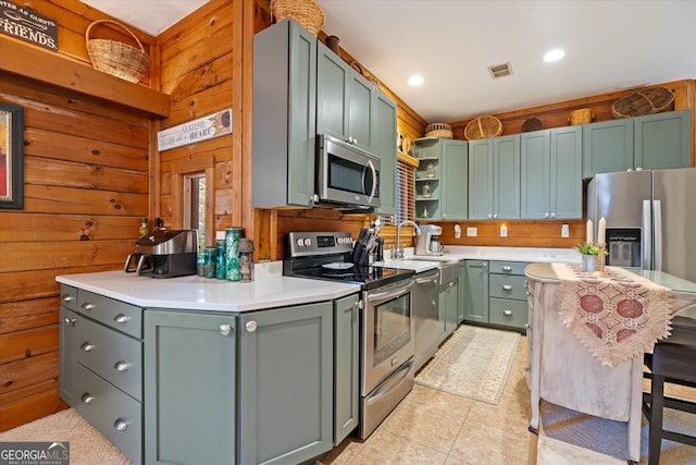 kitchen with wood walls, sink, light tile patterned floors, and stainless steel appliances