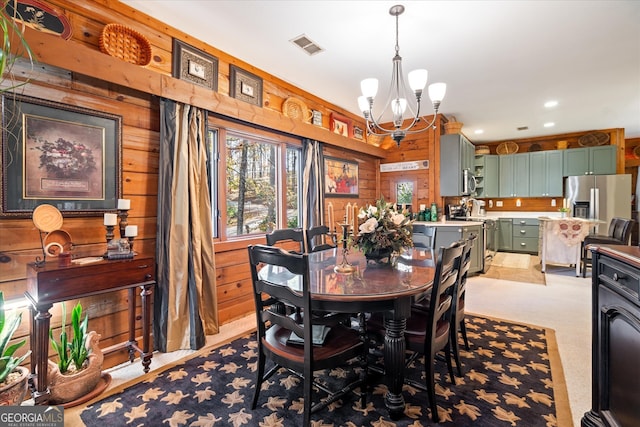 carpeted dining space with wooden walls and an inviting chandelier