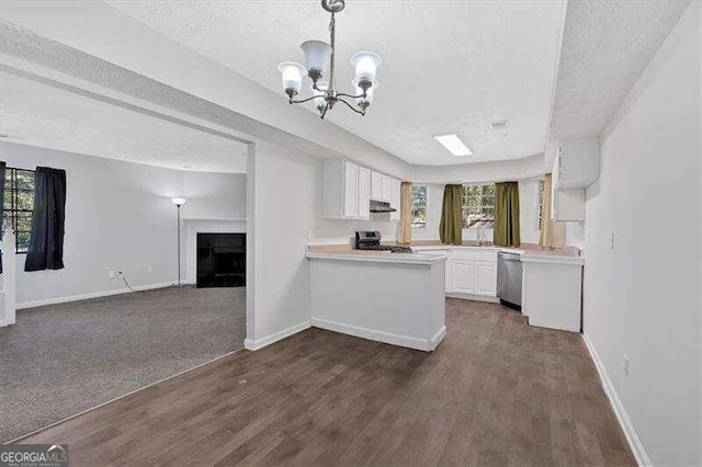 kitchen with kitchen peninsula, appliances with stainless steel finishes, a textured ceiling, white cabinets, and dark hardwood / wood-style floors