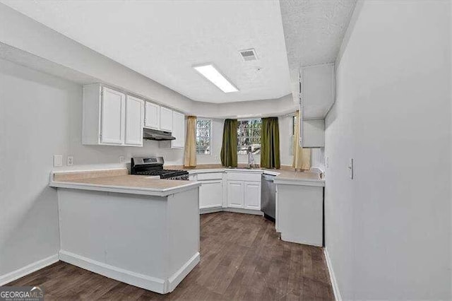 kitchen with dark hardwood / wood-style flooring, kitchen peninsula, a textured ceiling, white cabinets, and appliances with stainless steel finishes