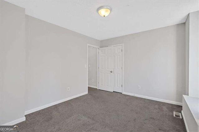 unfurnished room featuring dark carpet