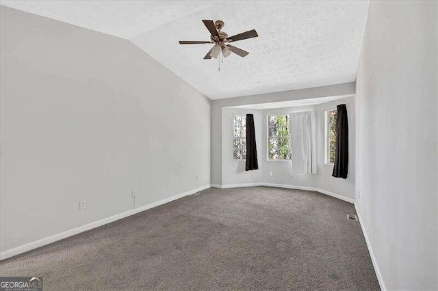 empty room with carpet flooring, ceiling fan, lofted ceiling, and a textured ceiling