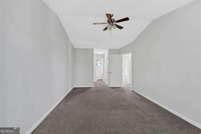 spare room with ceiling fan, lofted ceiling, and dark colored carpet