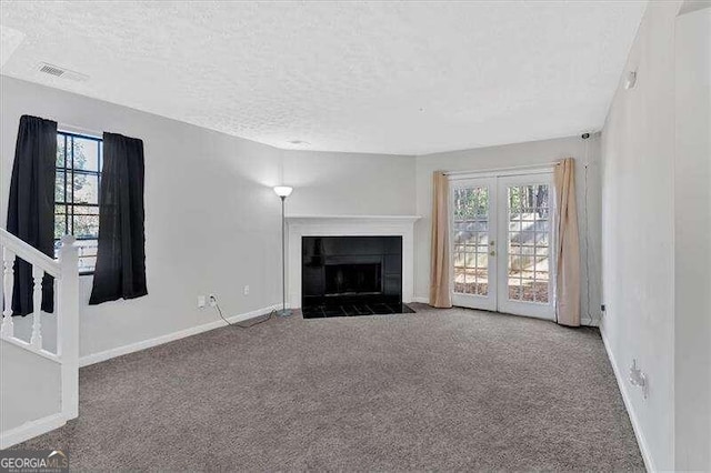 unfurnished living room featuring carpet flooring, a textured ceiling, and a wealth of natural light