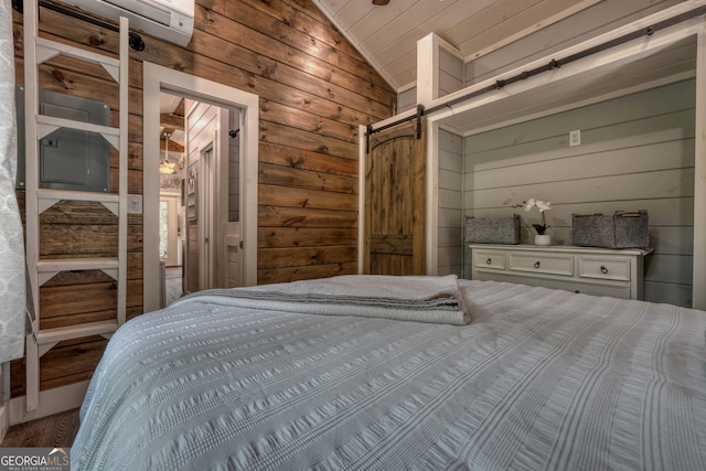 bedroom with vaulted ceiling, a barn door, and wooden walls