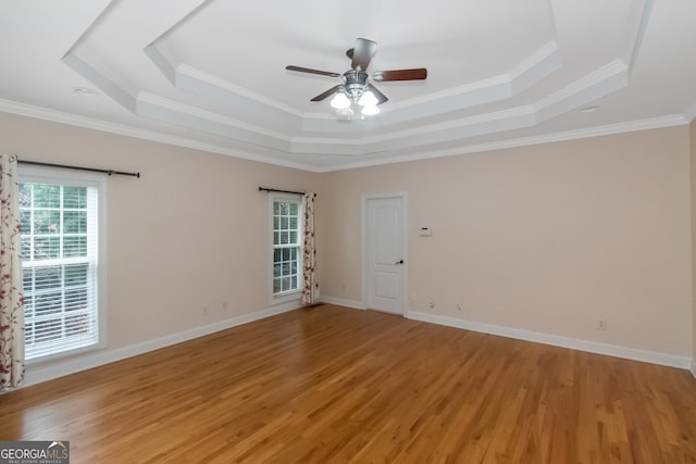 spare room with a tray ceiling, ceiling fan, light hardwood / wood-style floors, and ornamental molding