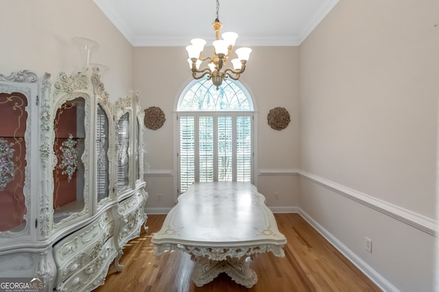 dining room with ornamental molding, a notable chandelier, and hardwood / wood-style flooring