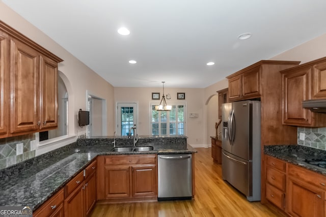 kitchen featuring pendant lighting, sink, decorative backsplash, light wood-type flooring, and appliances with stainless steel finishes