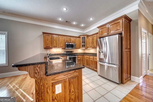 kitchen with light hardwood / wood-style flooring, ornamental molding, a textured ceiling, kitchen peninsula, and stainless steel appliances