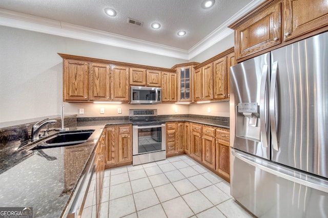 kitchen featuring appliances with stainless steel finishes, dark stone counters, a textured ceiling, crown molding, and sink