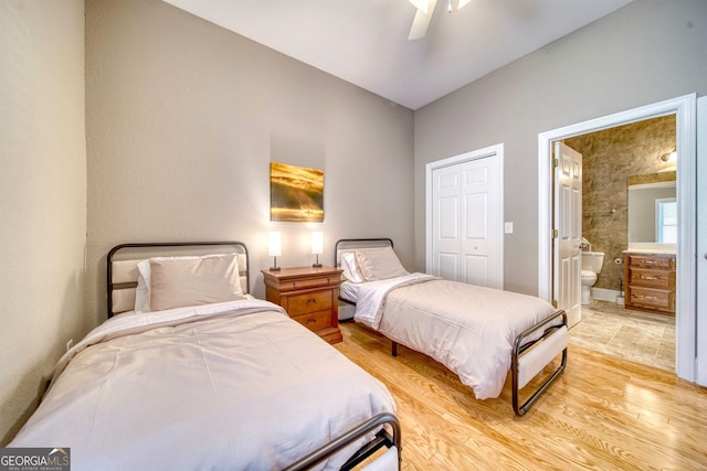 bedroom featuring ceiling fan, a closet, connected bathroom, and light hardwood / wood-style flooring