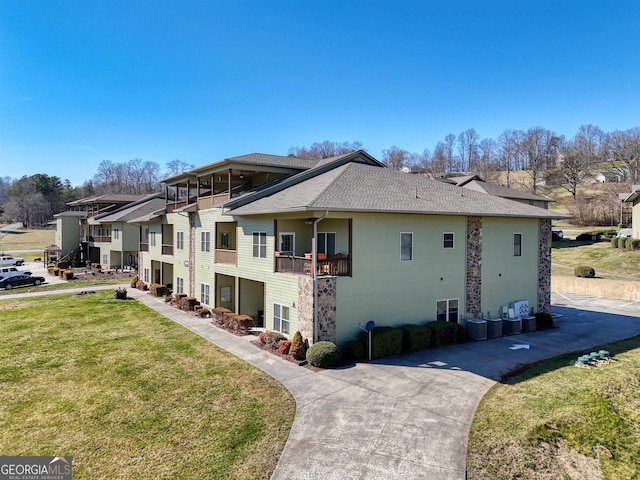 view of home's exterior with a lawn, a balcony, and central AC