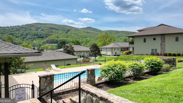 view of swimming pool with a lawn, a mountain view, and a patio