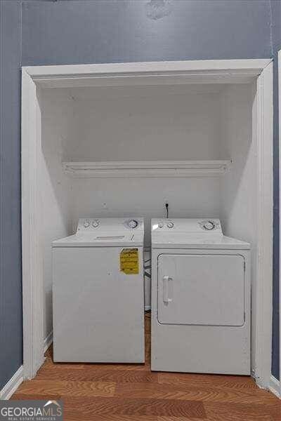 clothes washing area with washer and clothes dryer and wood-type flooring