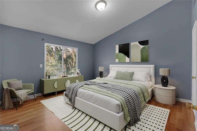 bedroom with wood-type flooring and vaulted ceiling