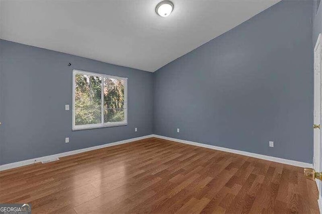 unfurnished room featuring hardwood / wood-style floors and vaulted ceiling