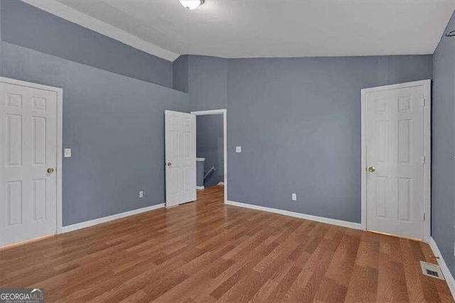 unfurnished bedroom featuring wood-type flooring and vaulted ceiling