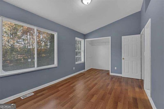 unfurnished bedroom featuring dark hardwood / wood-style flooring, a closet, multiple windows, and lofted ceiling