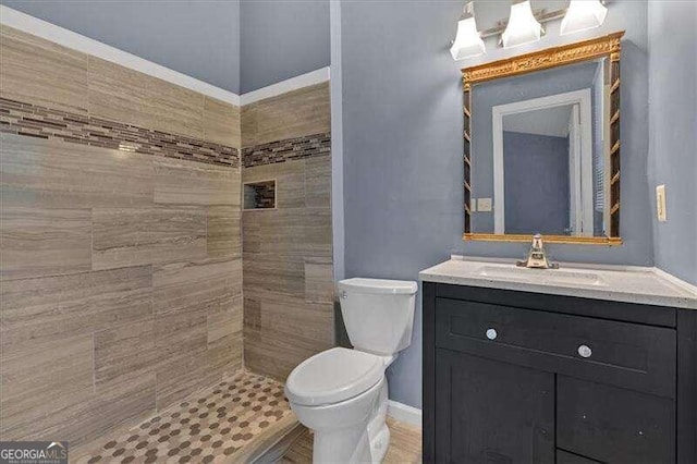 bathroom with vanity, toilet, and a tile shower