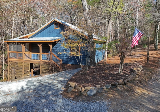 view of side of property featuring stairs and metal roof