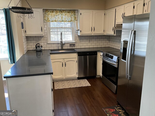 kitchen featuring sink, white cabinetry, stainless steel appliances, decorative backsplash, and decorative light fixtures