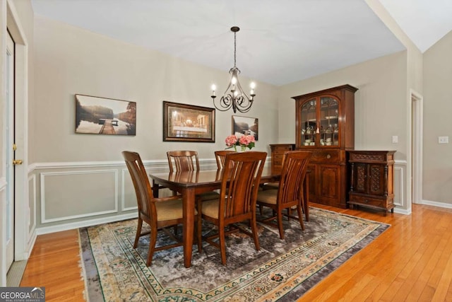 dining area with light hardwood / wood-style flooring, vaulted ceiling, and a notable chandelier