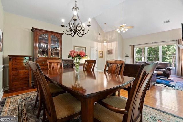 dining area featuring high vaulted ceiling, ceiling fan with notable chandelier, and hardwood / wood-style flooring