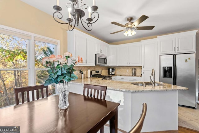 kitchen featuring white cabinetry, hanging light fixtures, light stone counters, and appliances with stainless steel finishes