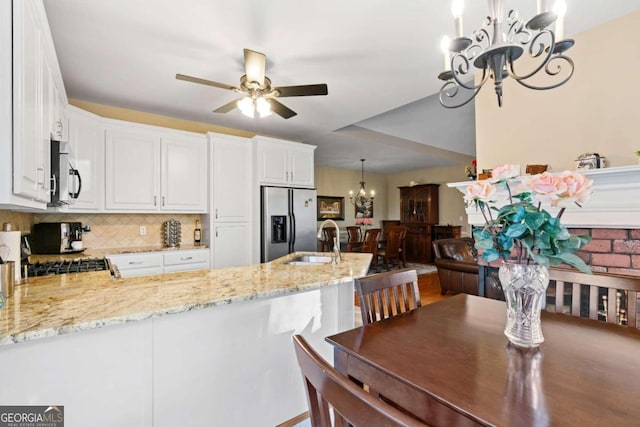 kitchen with sink, stainless steel appliances, kitchen peninsula, pendant lighting, and white cabinets