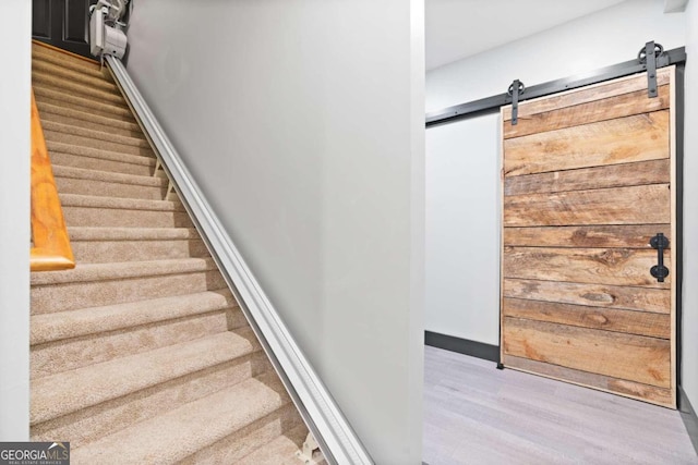 stairs with hardwood / wood-style floors and a barn door