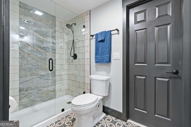 bathroom featuring tile patterned flooring, toilet, and a shower with door