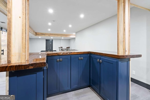 kitchen with kitchen peninsula, light wood-type flooring, and blue cabinetry