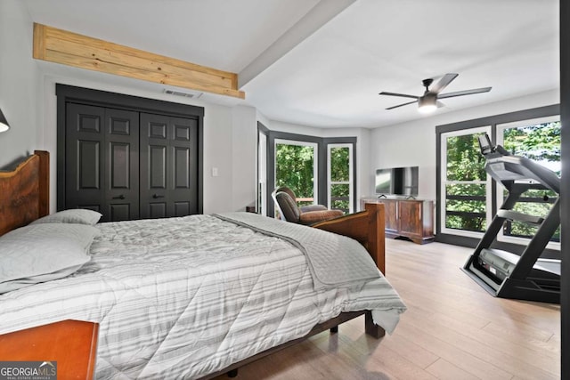 bedroom featuring ceiling fan, a closet, beamed ceiling, and light wood-type flooring