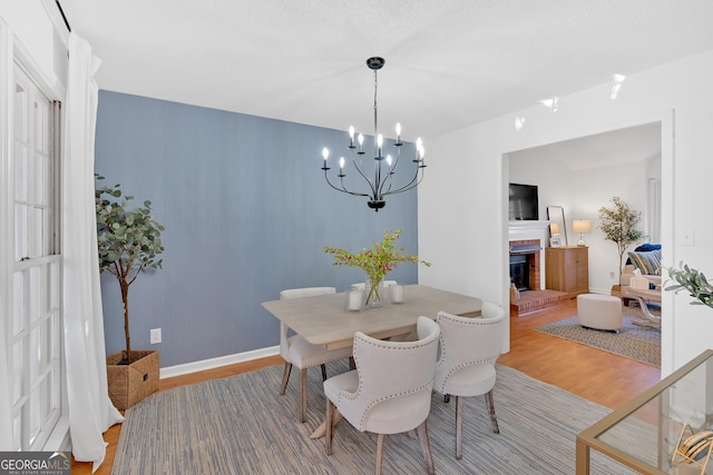 dining space with a brick fireplace, hardwood / wood-style floors, and a chandelier